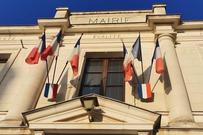 Façade d’une mairie pavoisée de drapeaux français